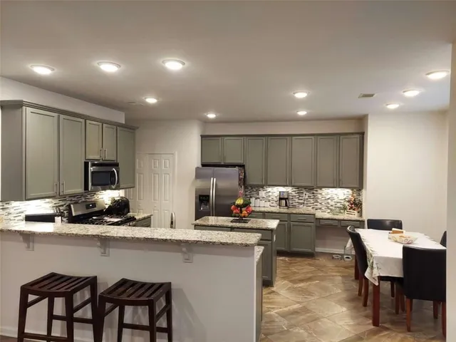 a kitchen with stainless steel appliances granite countertop a stove top oven a sink dishwasher a dining table and chairs with wooden floor