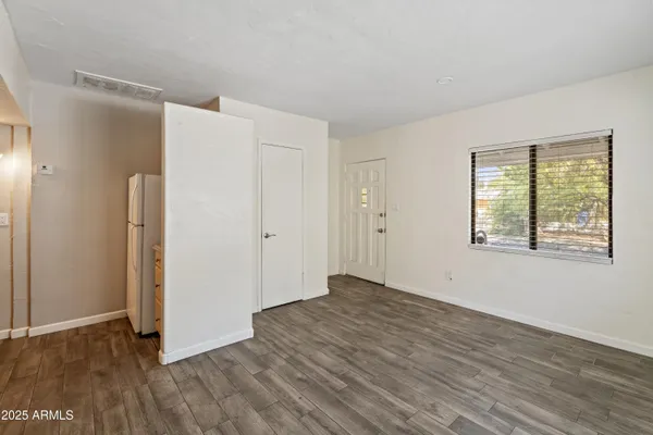 a view of an empty room with wooden floor and a window
