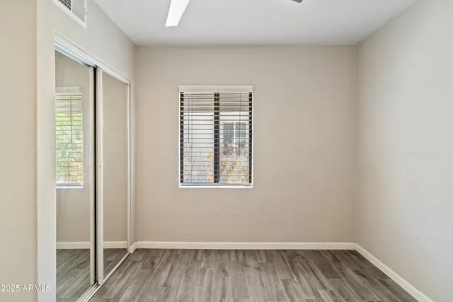 an empty room with wooden floor and windows