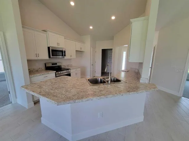 a large kitchen with stainless steel appliances granite countertop a stove a sink and a refrigerator