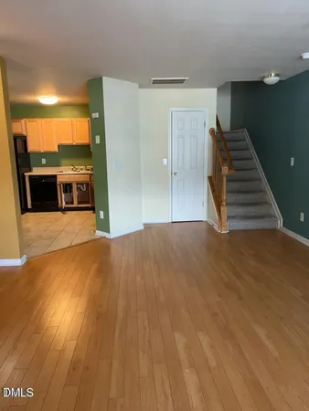 a view of a furniture and an empty room with wooden floor