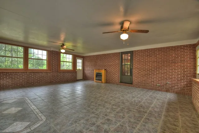 a view of an empty room with a window and a kitchen