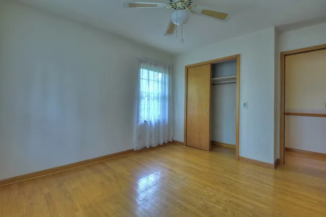 a view of an empty room with glass door and a chandelier fan