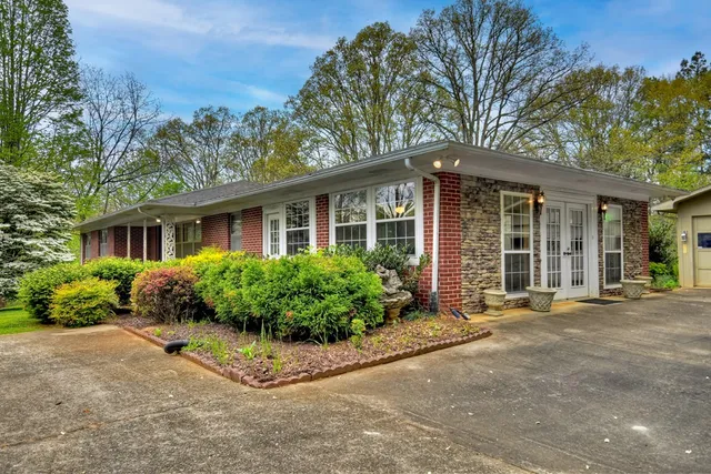 a view of a house with a small yard and floor to ceiling window and potted plants