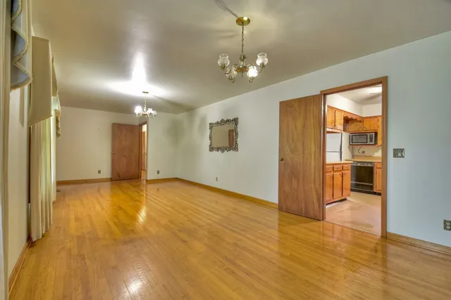 an empty room with chandelier fan and windows
