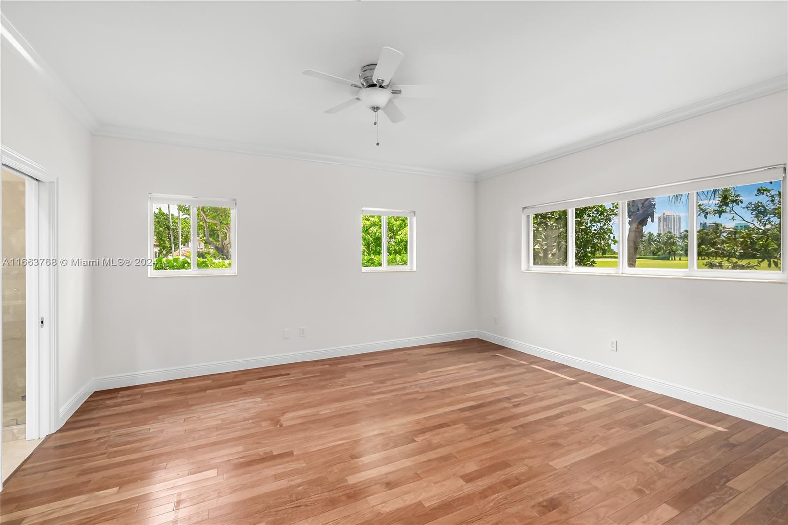 5785 Alton Road Miami Beach, FL 33140 - Photo 14 of 46 a view of an empty room with a window and wooden floor