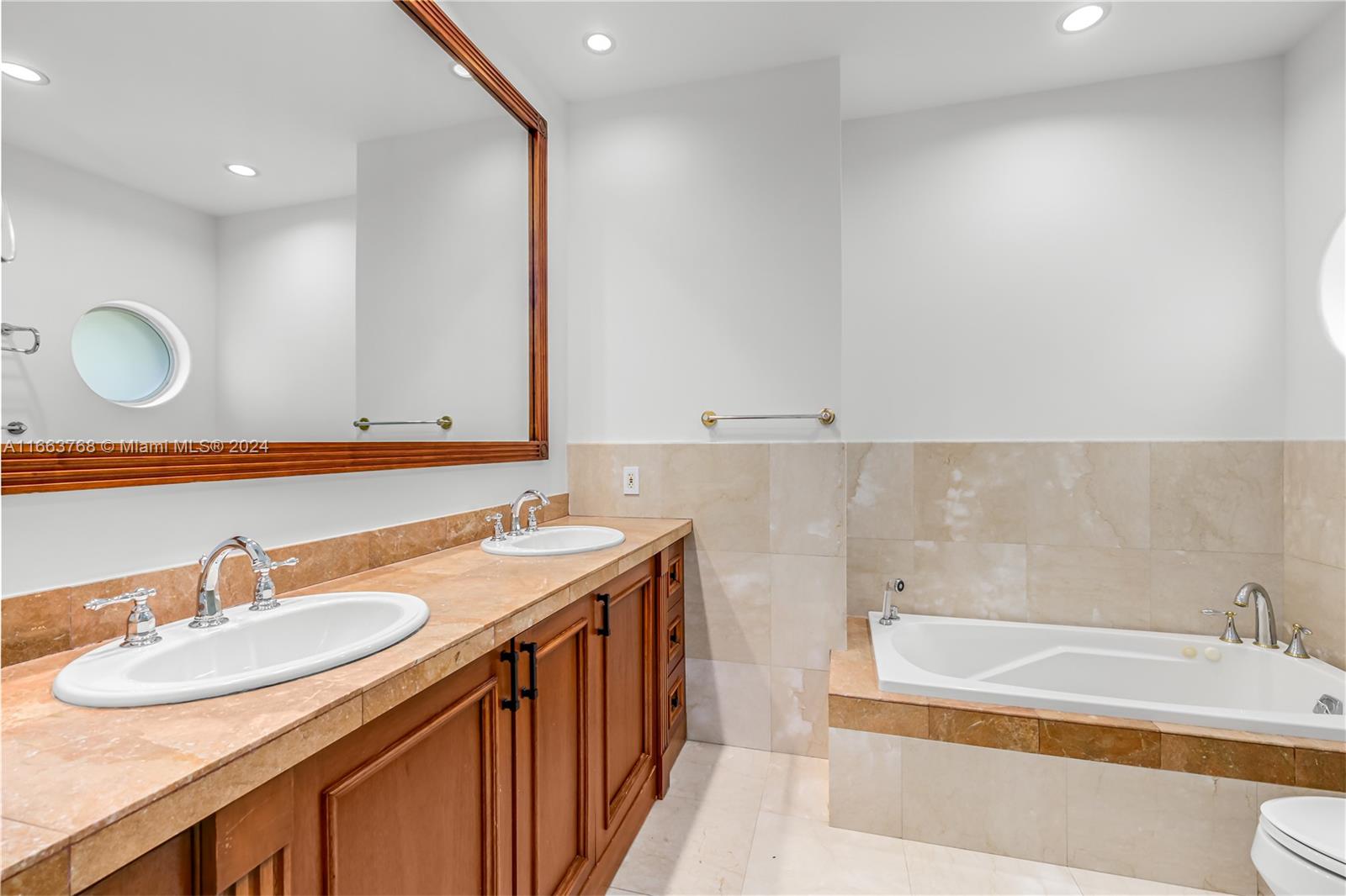 5785 Alton Road Miami Beach, FL 33140 - Photo 18 of 46 a bathroom with a granite countertop sink and a bathtub