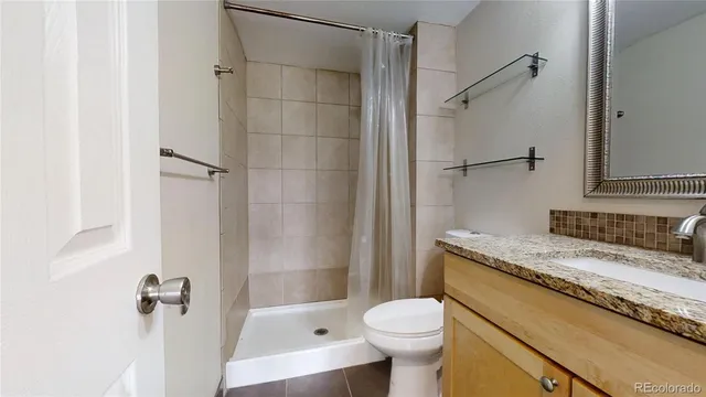 a bathroom with a granite countertop toilet and a shower