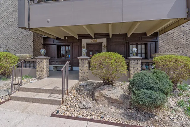 a front view of multi story residential apartment building with yard and traffic signal