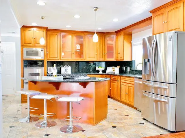 a kitchen with stainless steel appliances granite countertop a refrigerator and wooden cabinets