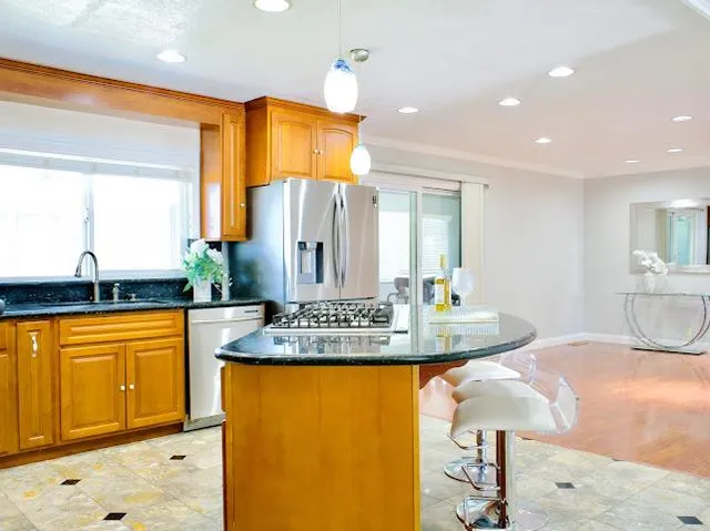 a view of a kitchen with kitchen island a counter top space a sink stainless steel appliances and cabinets