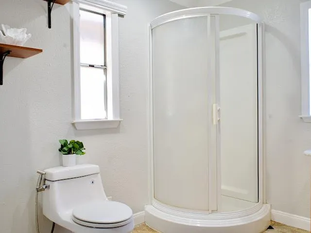 a white toilet sitting next to a shower