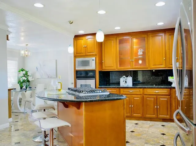 a kitchen with stainless steel appliances granite countertop a sink a stove and a wooden cabinets