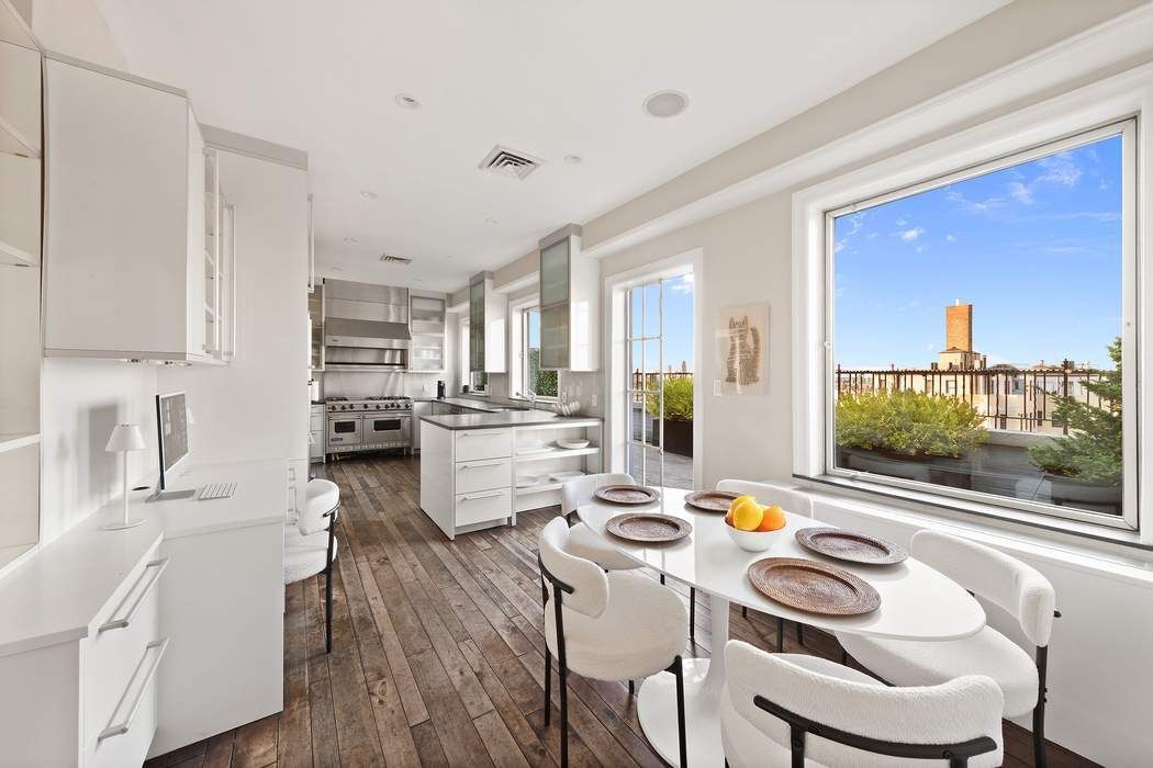 1158 5th Avenue, Unit PHC Manhattan, NY 10128 - Photo 9 of 25 a kitchen with a table chairs stove and white cabinets