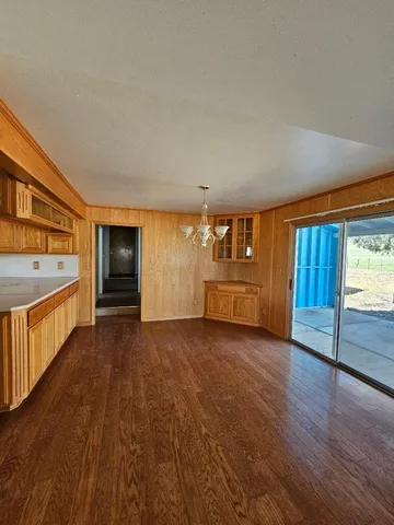 a view of an empty room with a kitchen and a window