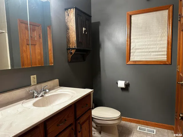a bathroom with a granite countertop sink toilet and mirror