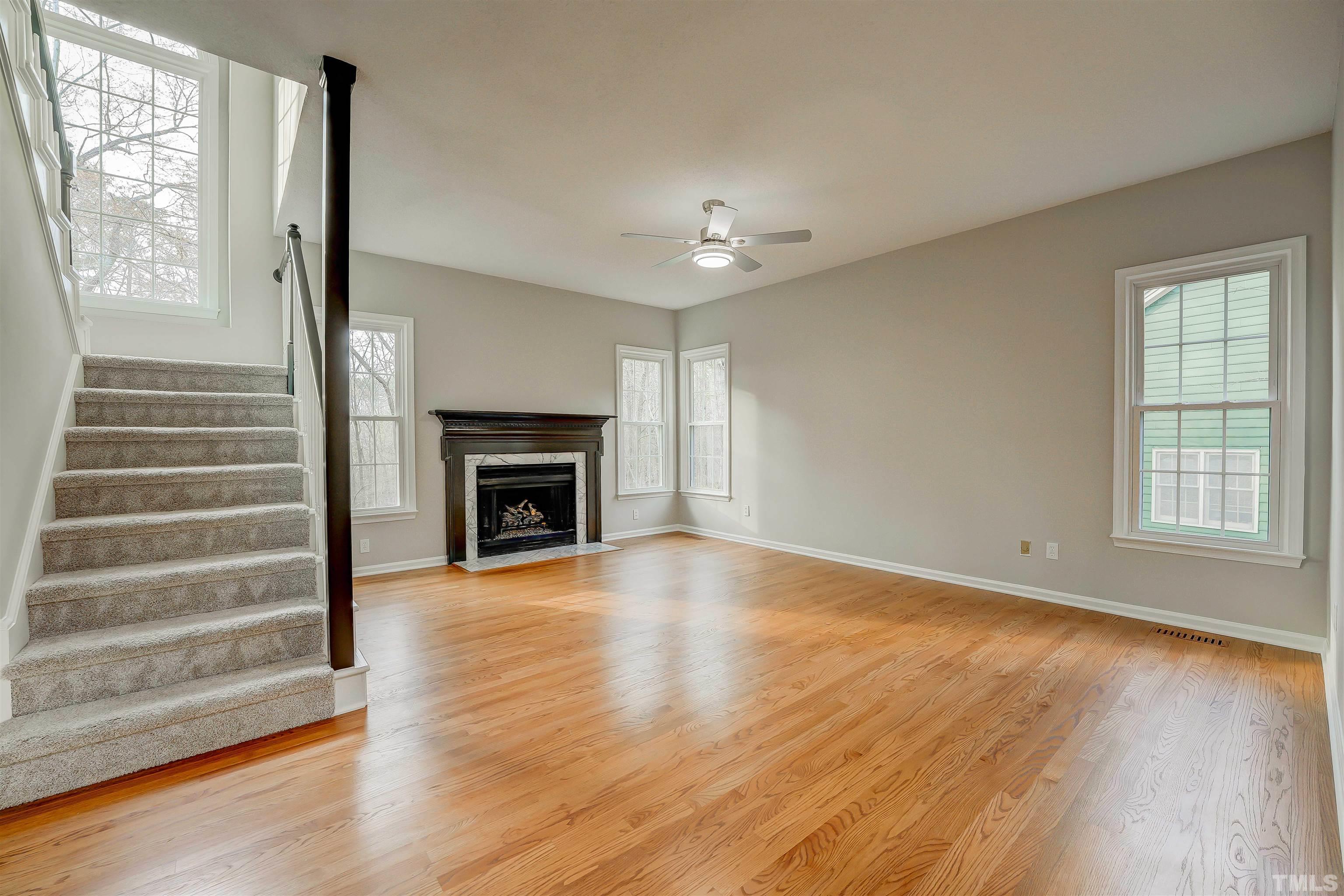 5516 Bridford Place Raleigh, NC 27613 - Photo 6 of 20 an empty room with wooden floor fireplace and windows