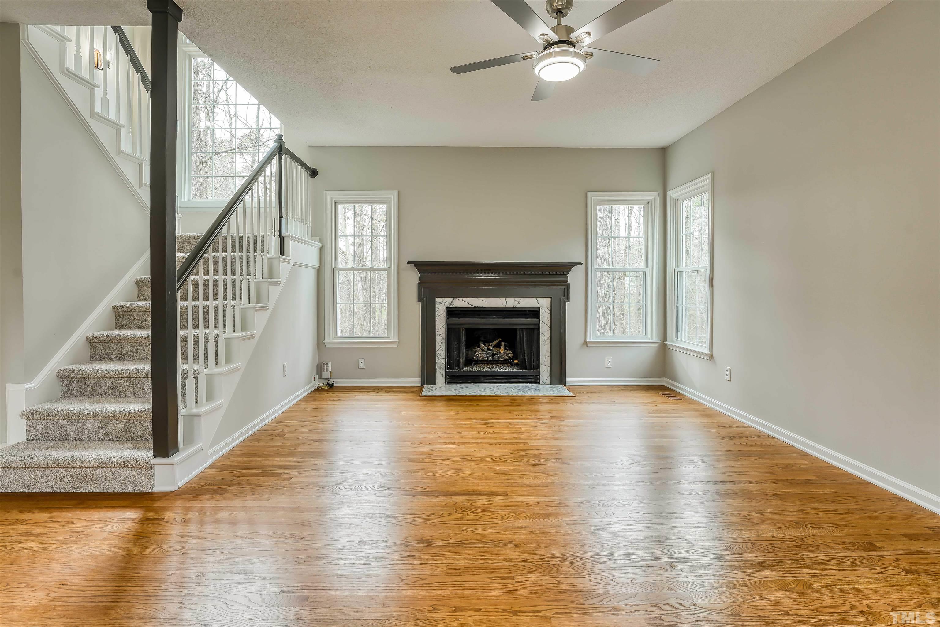 5516 Bridford Place Raleigh, NC 27613 - Photo 7 of 20 a view of an empty room with wooden floor fireplace and a window