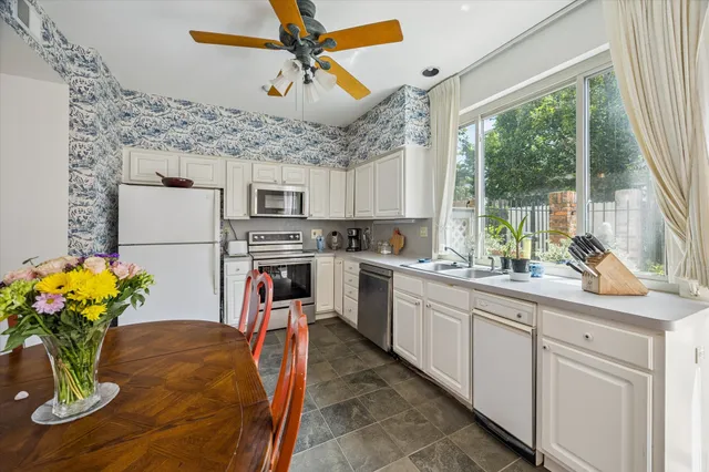 a kitchen with stainless steel appliances granite countertop a refrigerator a sink dishwasher a microwave oven with a dining table and chairs