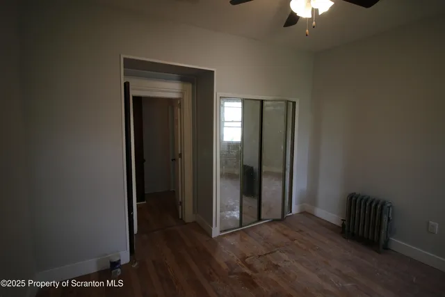 an empty room with wooden floor closet and chandelier fan