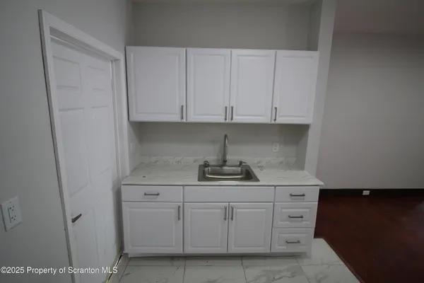 a kitchen with white cabinets and sink