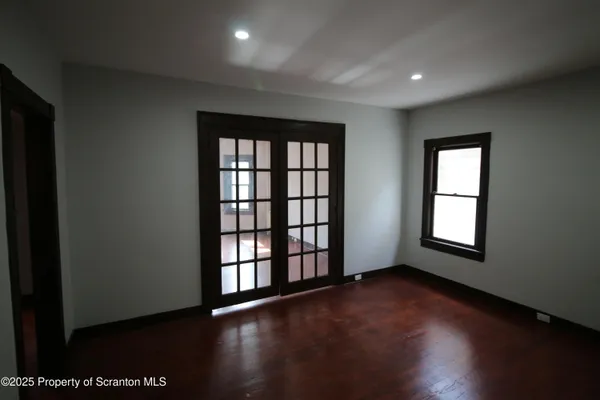 an empty room with wooden floor and windows