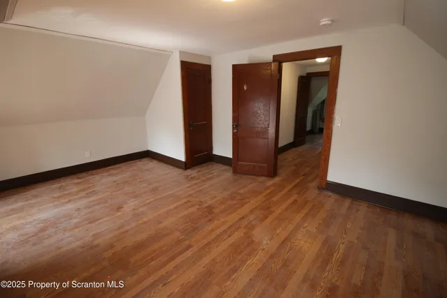 a view of an empty room with closet and wooden floor