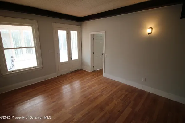 an empty room with wooden floor and windows