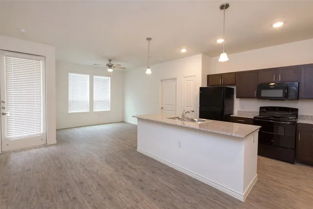 a large kitchen with stainless steel appliances a large counter top a stove and a refrigerator