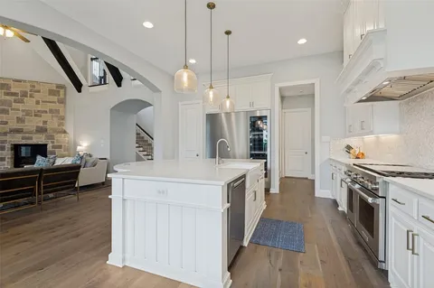 a large kitchen with cabinets wooden floor and a sink
