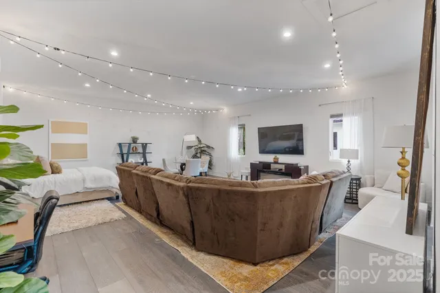 a living room with furniture potted plant and open kitchen view