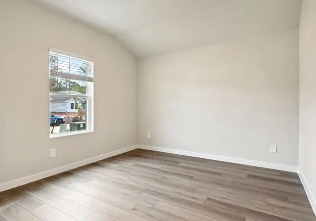 an empty room with wooden floor and windows