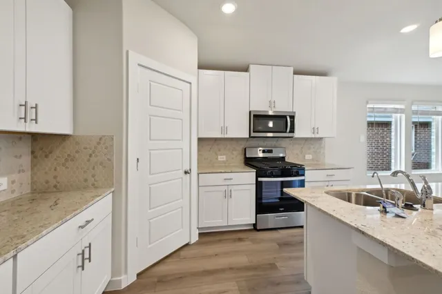 a kitchen with granite countertop white cabinets and stainless steel appliances