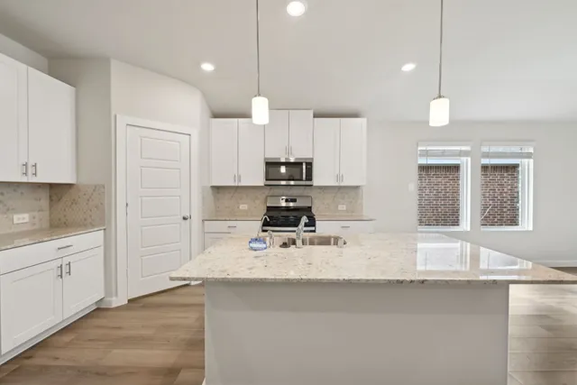 a kitchen with kitchen island white cabinets stainless steel appliances and a center island