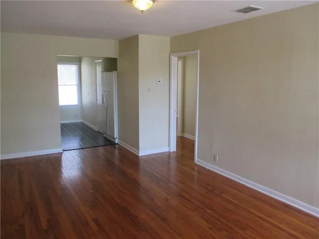an empty room with wooden floor & windows