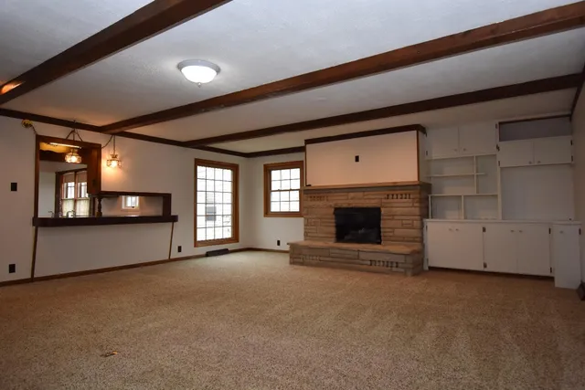 a view of an empty room with a fireplace and a window