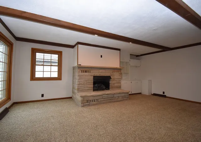 a view of an empty room with a fireplace and a window