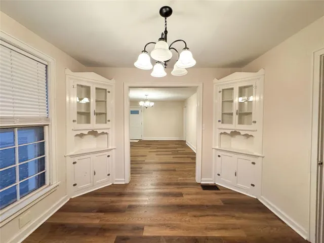 an empty room with wooden floor cabinet and windows