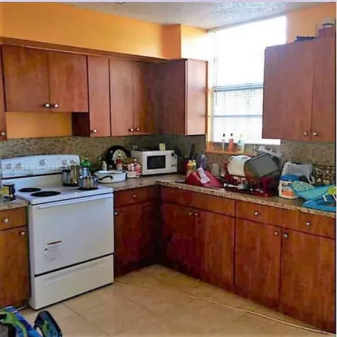 a kitchen with stainless steel appliances granite countertop a sink window and cabinets