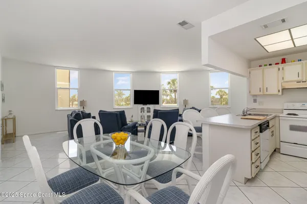 a kitchen with stainless steel appliances kitchen island granite countertop a sink a stove a dining table and chairs with wooden floor