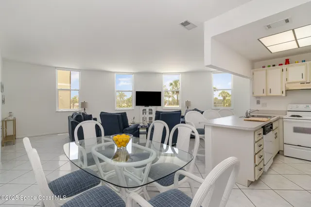 a kitchen with stainless steel appliances kitchen island granite countertop a sink a stove a dining table and chairs with wooden floor