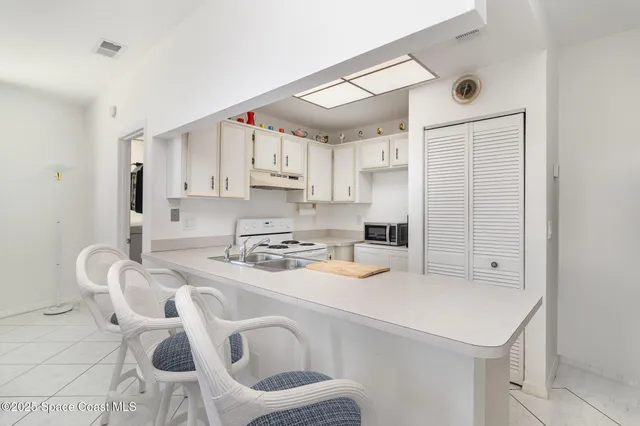 a kitchen with stainless steel appliances a white table chairs and a refrigerator
