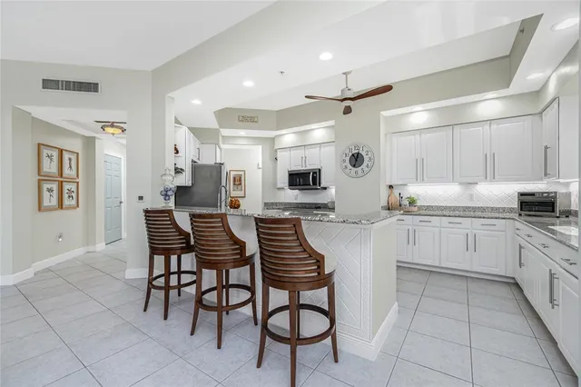 a kitchen with stainless steel appliances kitchen island granite countertop a refrigerator and a stove top oven