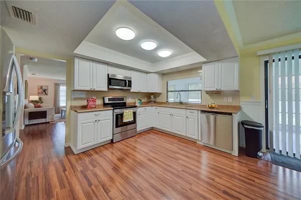 a kitchen with kitchen island granite countertop stainless steel appliances cabinets and wooden floor