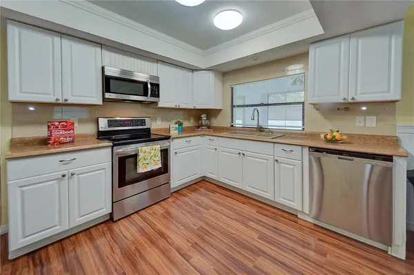 a kitchen with stainless steel appliances white cabinets granite counter tops and a hard wood floors