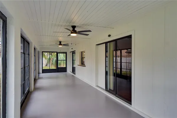 a view of a hallway with a chandelier fan and windows
