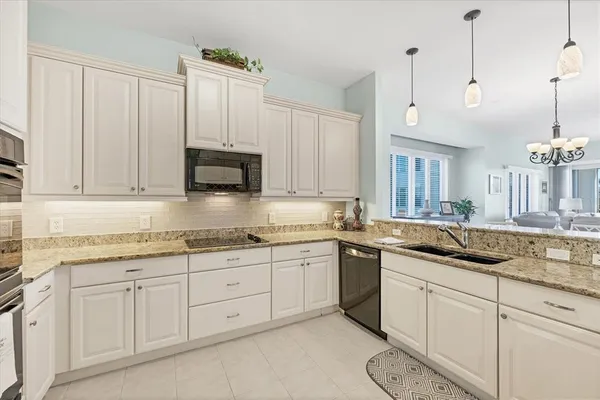 a kitchen with granite countertop a refrigerator sink and stainless steel appliances