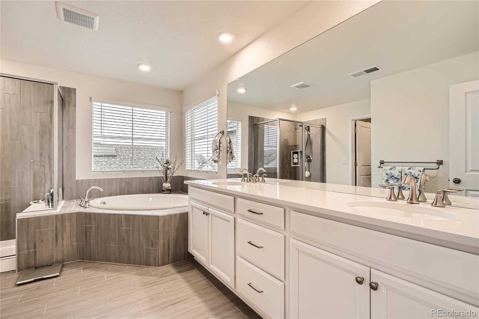 946 Compass Drive Erie, CO 80516 - Photo 16 of 28 a bathroom with double vanity sinks double vanity tub and a mirror