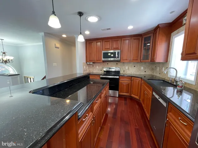 a kitchen with stainless steel appliances granite countertop a sink a stove top oven a counter space and cabinets