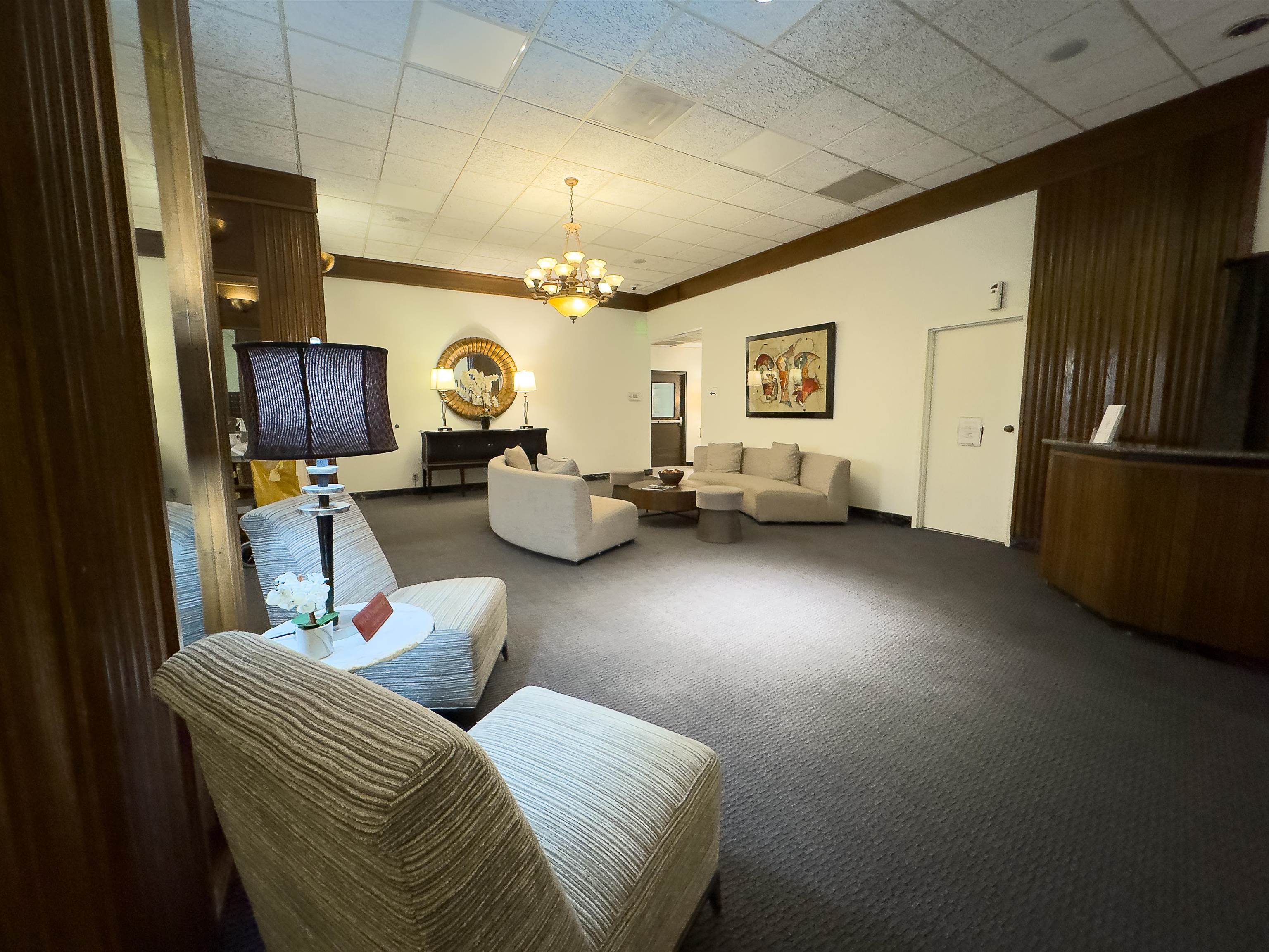 109 North Main Street, Unit 907 Memphis, TN 38103 - Photo 4 of 29 Spacious reception area featuring dark patterned carpeting, recessed lighting, and a multi-arm chandelier